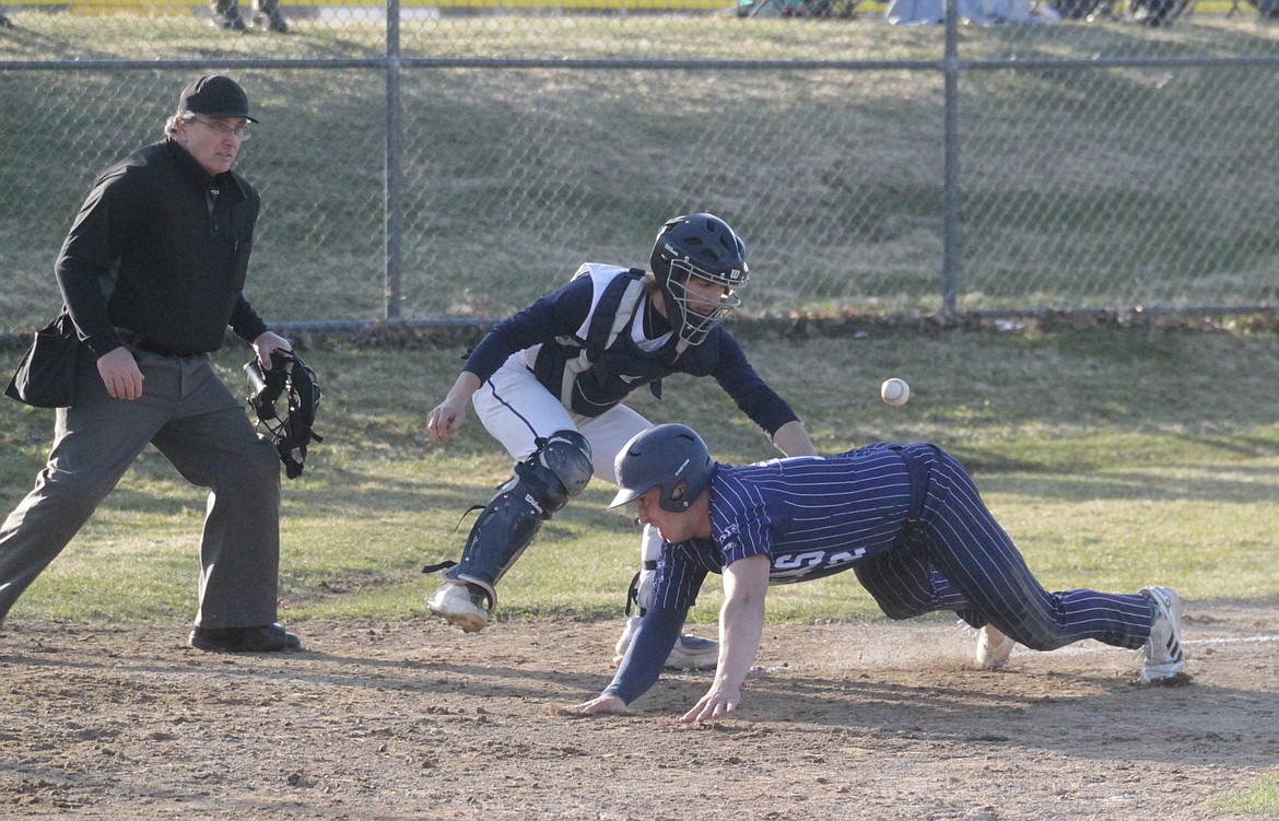 Blake Rice (12) of Bonners Ferry dives home safely with a run as Timberlake catcher Jesse O'Connor tries to snare the throw, after Rice escaped a rundown in the second game on Friday in Spirit Lake.