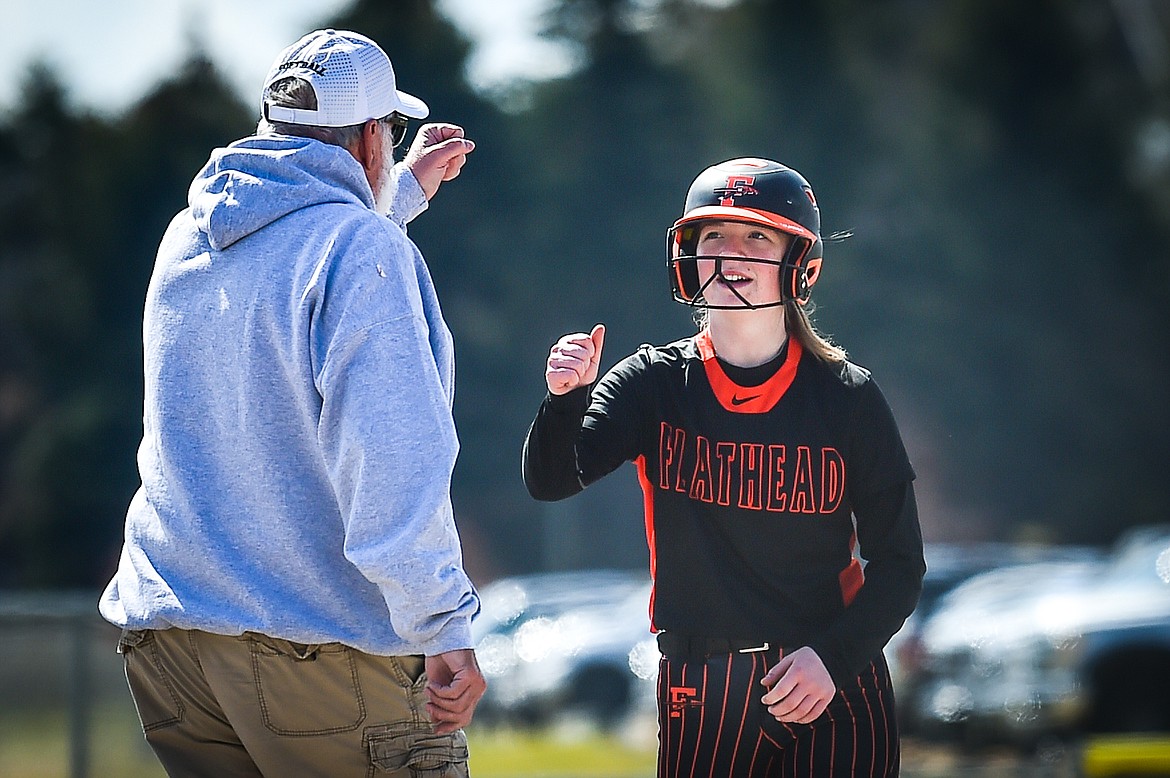 Flathead head coach Jack Foster congratulates MacKenzie Brandt (8) after her triple in the first inning against Helena at Kidsports Complex on Saturday, April 15. (Casey Kreider/Daily Inter Lake)