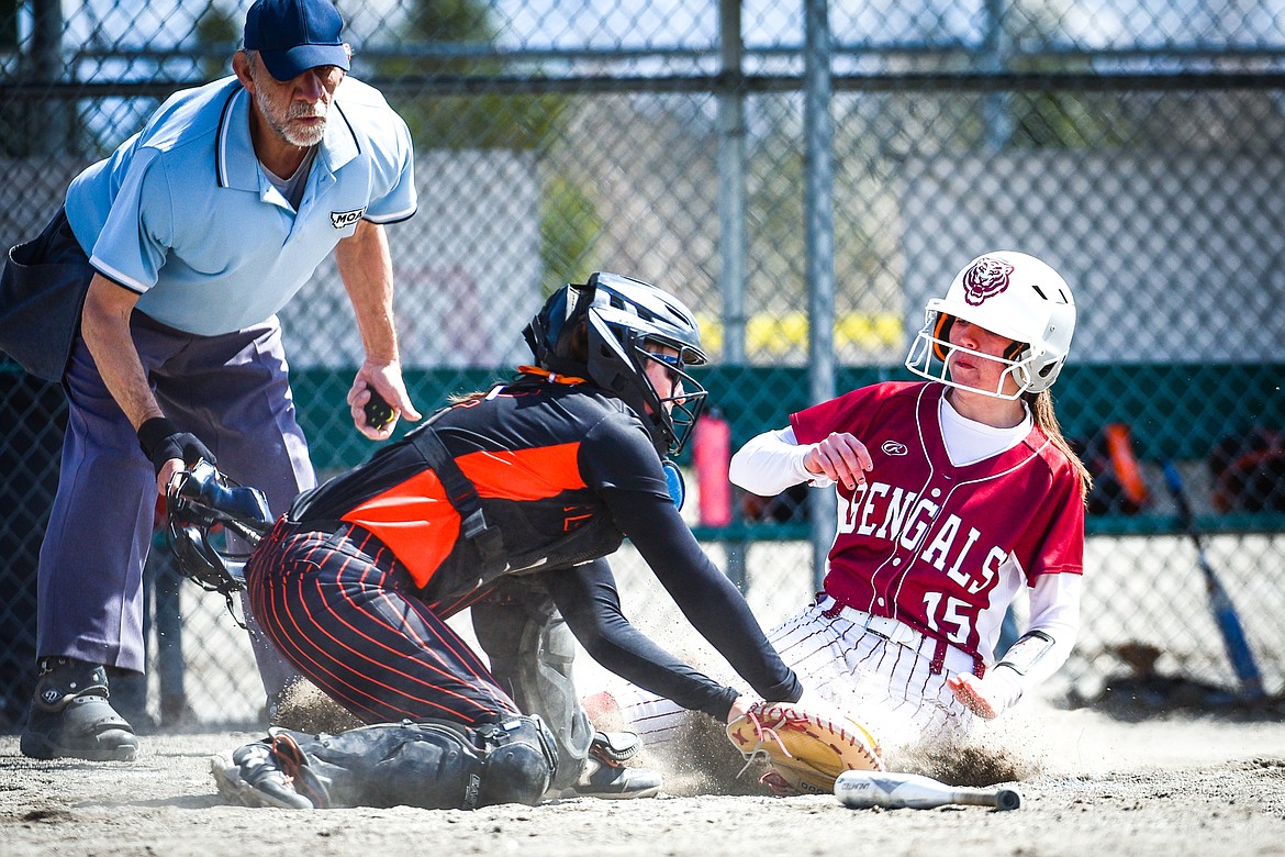 Helena's Mallory English (15) slides in just ahead of the tag by Flathead catcher Laynee Vessar (12) on a play at the plate in the fifth inning at Kidsports Complex on Saturday, April 15. (Casey Kreider/Daily Inter Lake)