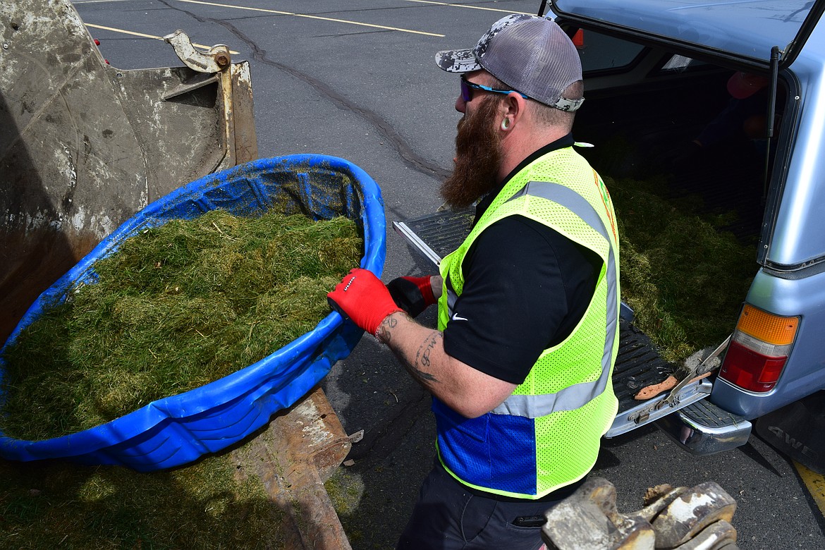 Joseph Allen, an employee with Lakeside Disposal, prepares to heave a kiddie pool full of grass clippings into the back of a garbage truck as part of the city’s Spring Clean Event on Saturday.