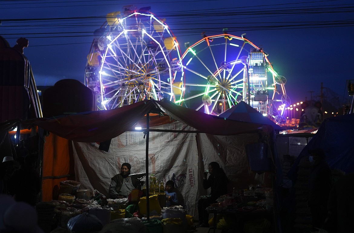 A grocery seller waits for customers at the "Feria de Ramos," or Palm Fair, in El Alto, Bolivia, Sunday, April 2, 2023. The Palm Fair, which began as a way to recreate the livestock markets of biblical times, is currently dominated by all sorts of informal trade. (AP Photo/Juan Karita)