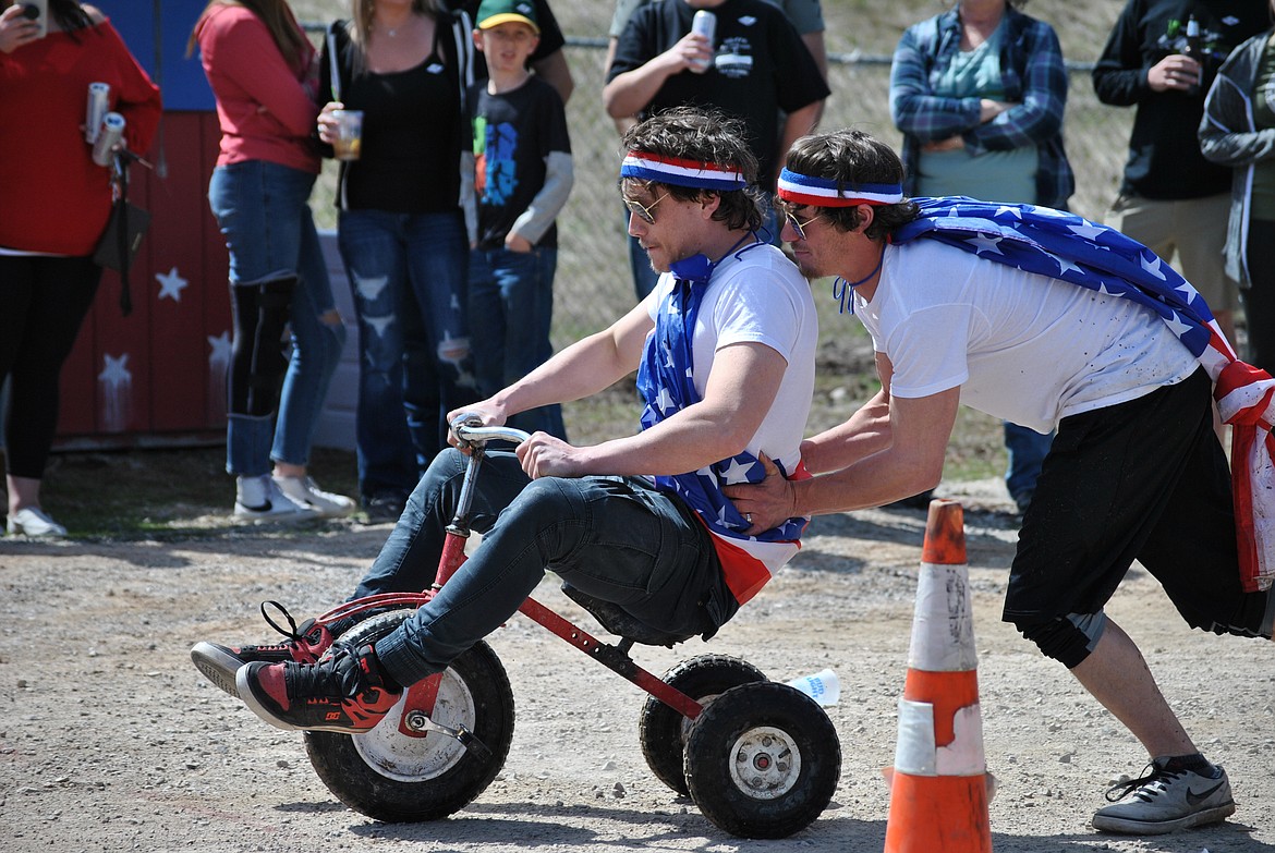 William Roper gives twin brother Cody Roper a big boost during the annual Talking Bird Saloon Tricycle Races in St. Regis on Saturday afternoon. The very patriotic team from St. Regis, dubbed the Caucasian Persuasion, took first place. Troy Chatterly and Rick Forthoffer were the other two racers on the champion four man team. (Amy Quinlivan/Mineral Independent)