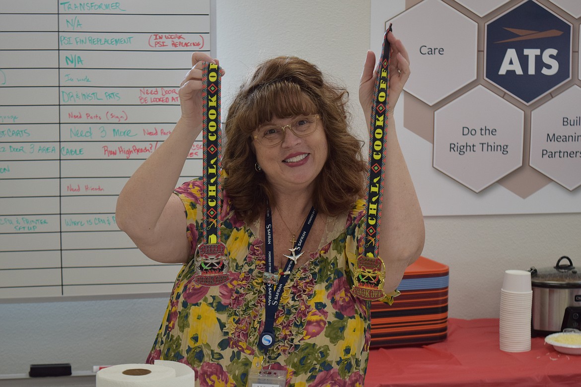 Amy Ward, an administrative assistant at Greenpoint Technologies, holding up the first- and second-place medals awarded for the best chili at one of the company’s regular morale-boosting events, its annual chili cookoff on Monday.