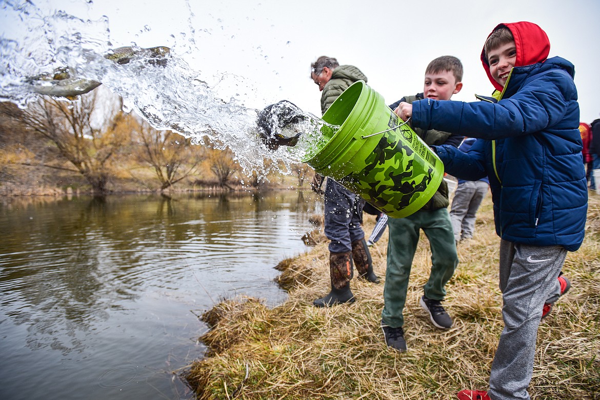 Hedges Elementary school fourth-graders Beckett Roach and Anderson Pelc pour a bucket of rainbow trout into the water at Dry Bridge Park during a Hooked On Fishing program held by Montana, Fish Wildlife & Parks on Wednesday, April 19. (Casey Kreider/Daily Inter Lake)