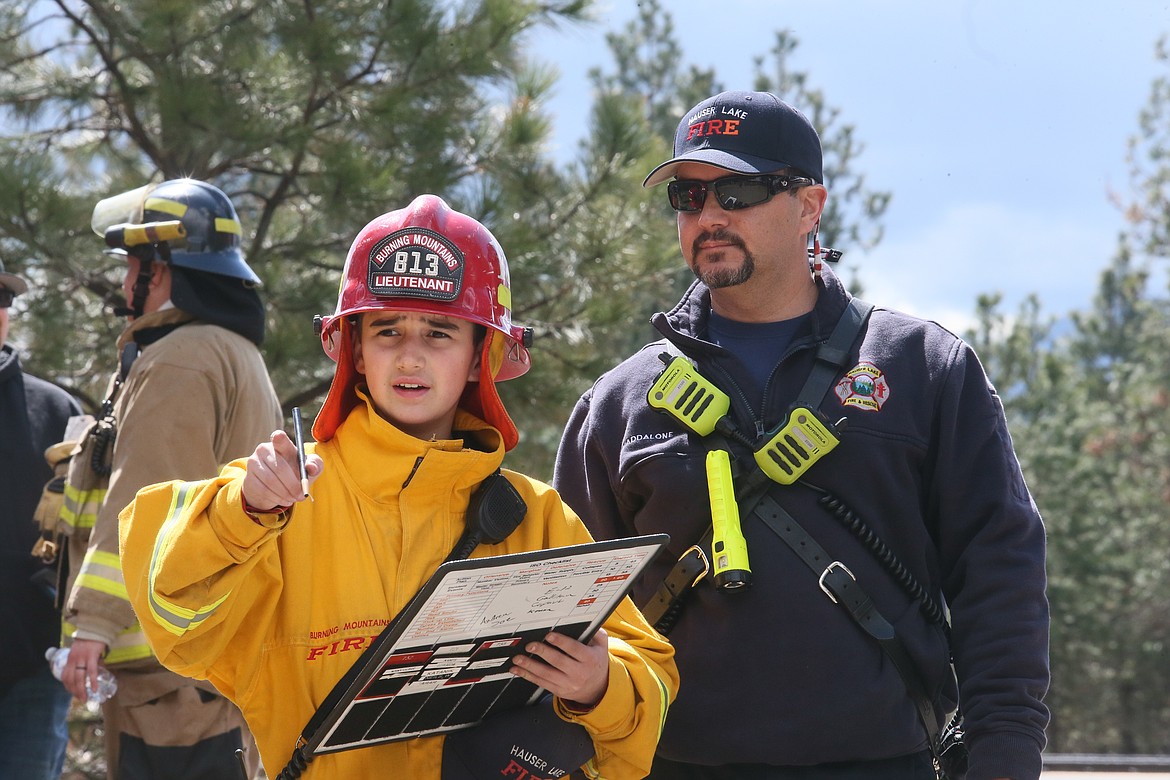 Future firefighter Beau Maddalone, 12, observes a house burning training exercise with his dad, Hauser Fire Deputy Chief Thomas Maddalone, on Saturday at Pleasant View Road and Highway 53.