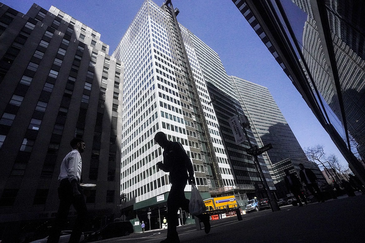 A pedestrian is silhouetted against a high rise at 160 Water Street in Manhattan's financial district, as the building is undergoing a conversion to residential apartments, Tuesday, April 11, 2023, in New York. (AP Photo/Bebeto Matthews)