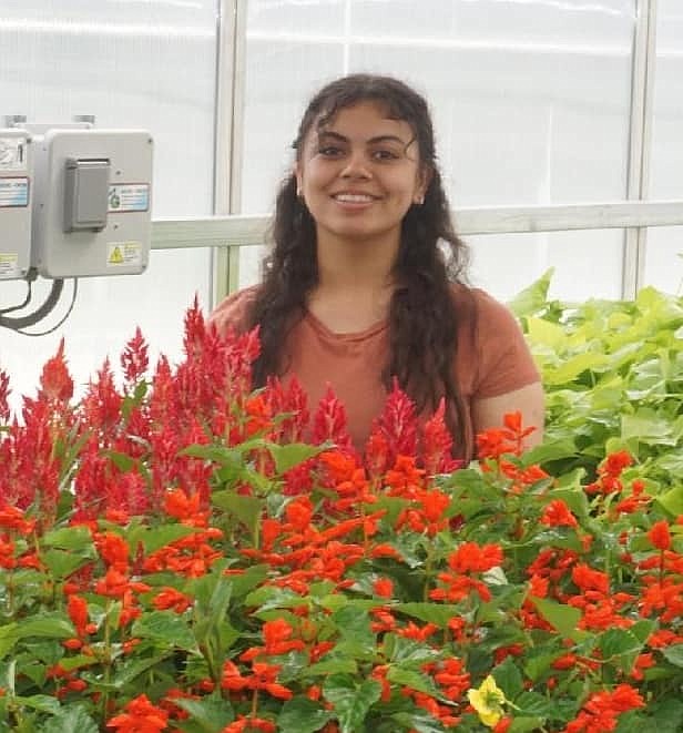 Areille Morga shows off some of the flowers in the QHS greenhouse.