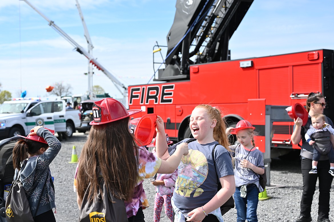 A pair of girls laughs in front of a large fire truck during the Mothers of Preschoolers Touch a Truck fundraiser in Moses Lake on Saturday.