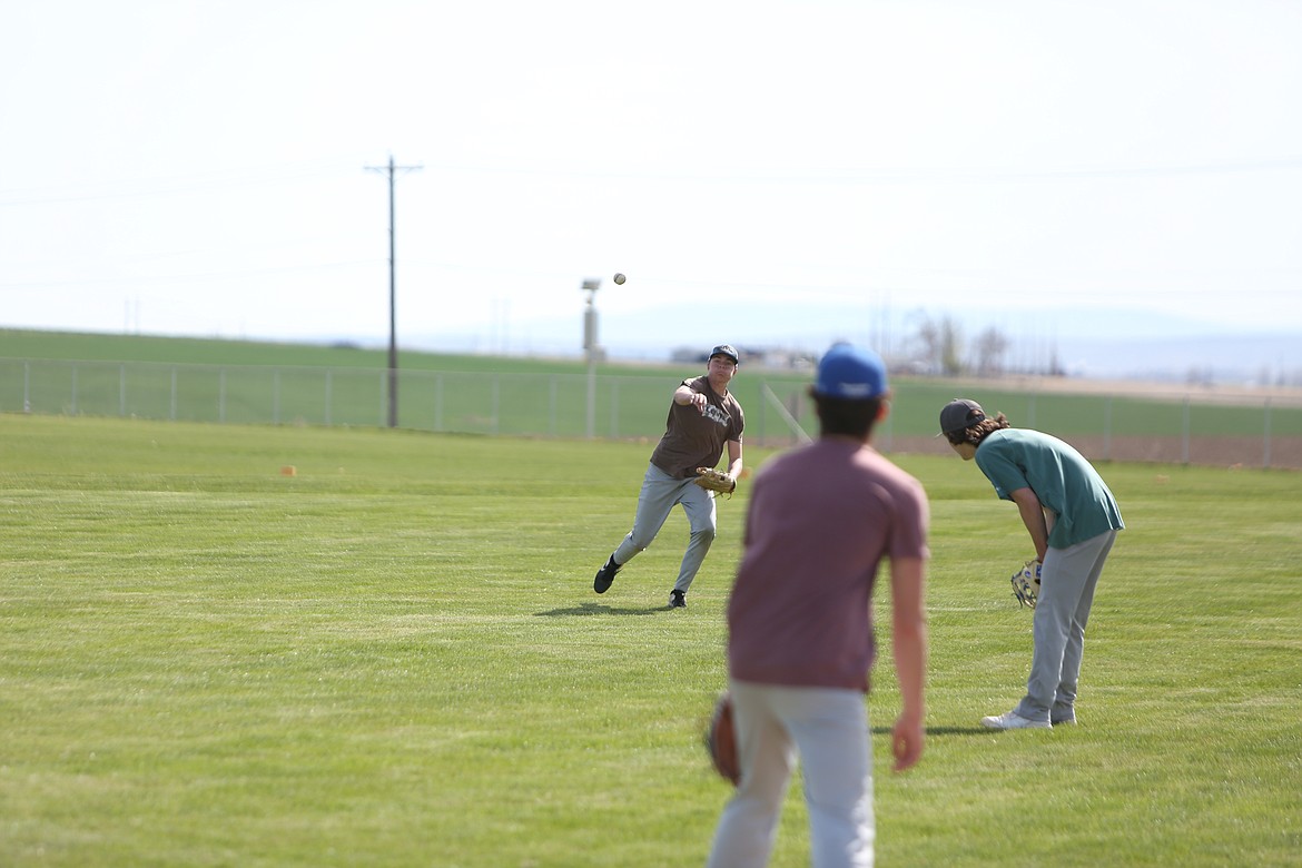 Warden senior Carson Watkins, brown shirt, throws a ball to third base during a Cougar practice on Tuesday.