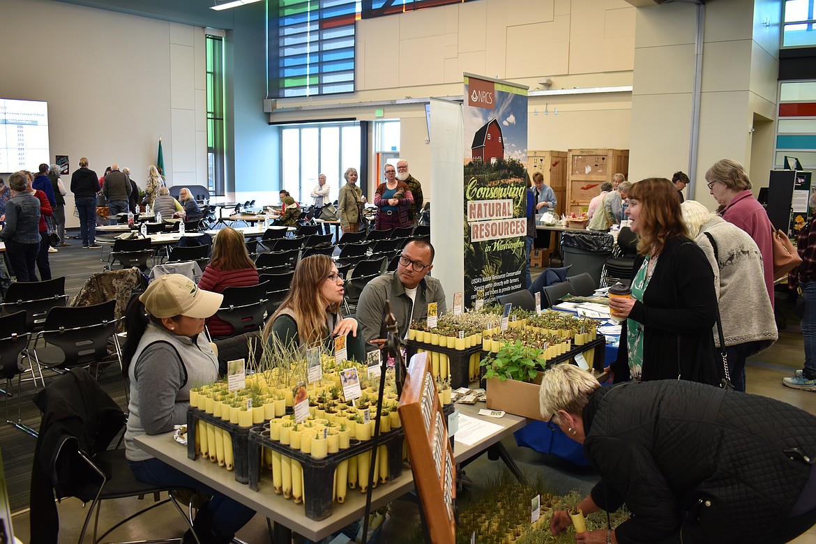 From left: Edith Gonzalez, Linda Duran and Rico Duran, of BFI Natural Seeds, discuss a variety of plants with attendees at the Columbia Basin Eco-Gardening Symposium Saturday.