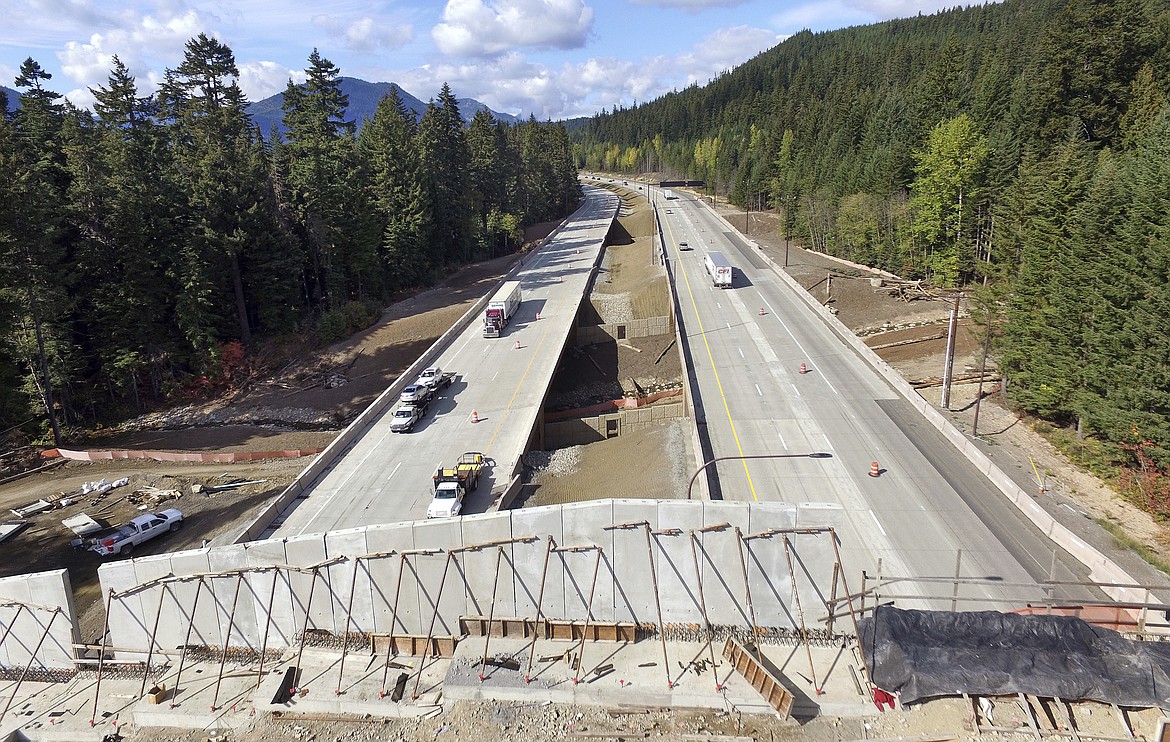 In this photo taken Oct. 4, 2018, Interstate 90 traffic passes beneath a wildlife bridge under construction on Snoqualmie Pass, Wash. The stretch of highway crossing the Cascade Mountains cuts through old-growth forest and wetlands, creating a dangerous border for wildlife, everything from an elk down to a small salamander.