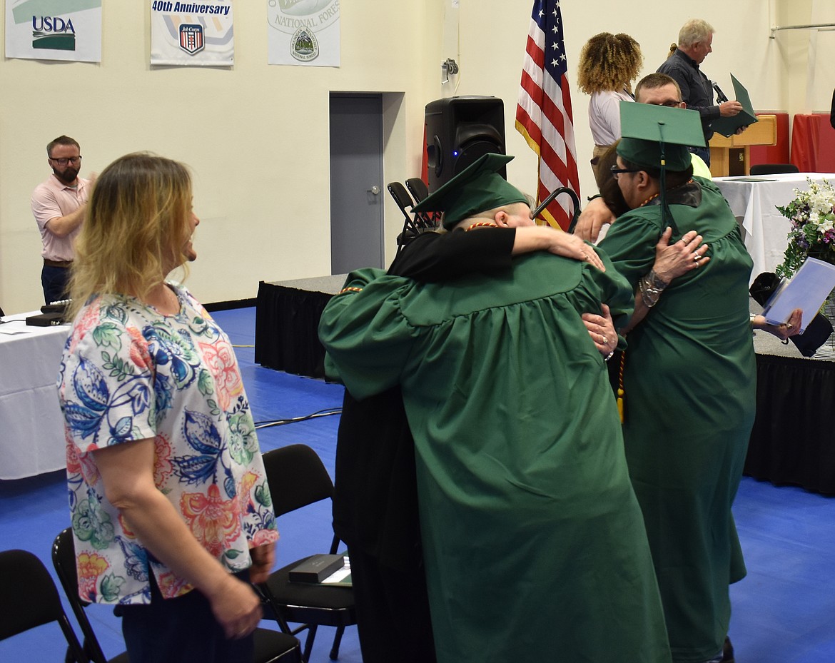 New Job Corps graduates Micheal Baker Jr., left, and Isaias Alvarez stop to hug some of their instructors after receiving their certificates.