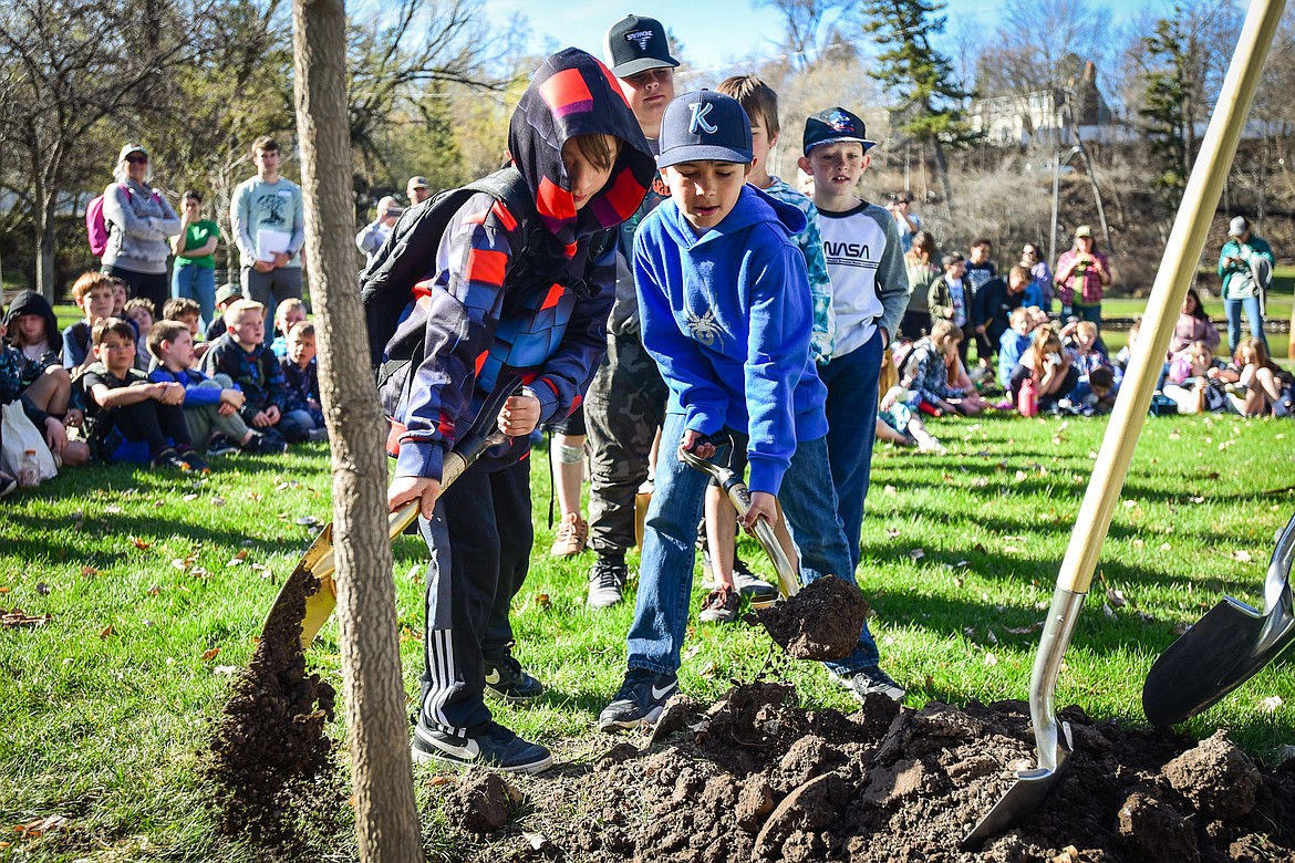 Third-grade students shovel dirt as a hackberry tree the students voted to name "Howard" is planted at the Arbor Day celebration in Woodland Park on Friday, April 28. (Casey Kreider/Daily Inter Lake)