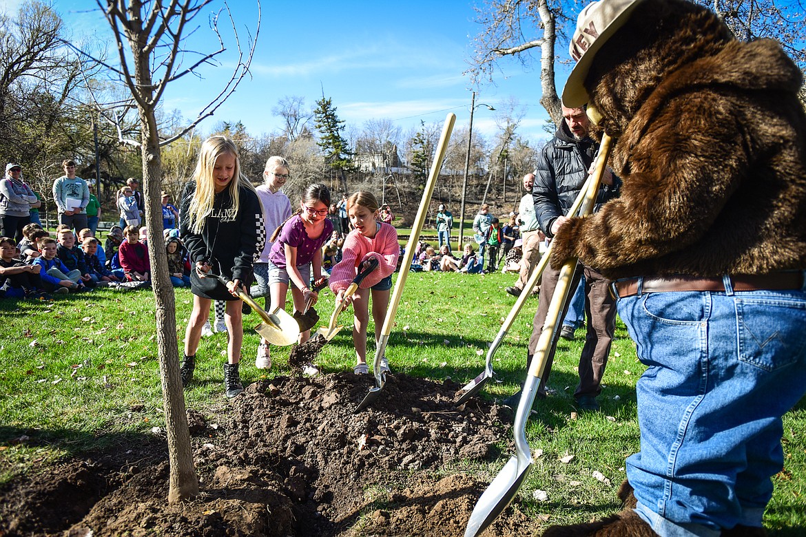 Third-grade students shovel dirt with Smokey the Bear as a hackberry tree the students voted to name "Howard" is planted at the Arbor Day celebration in Woodland Park on Friday, April 28. (Casey Kreider/Daily Inter Lake)
