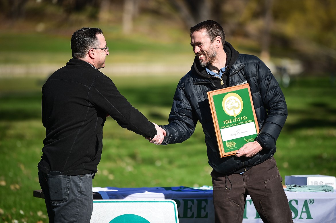 Matt Arno, left, the Forestry Assistant Bureau Chief for the Department of Natural Resources and Conservation, presents the Tree City USA Growth Award to  Kalispell City Councilor Ryan Hunter, accepting on behalf of the city, at the Arbor Day celebration at Woodland Park on Friday, April 28. It is the 36th year that Kalispell has been recognized by the Arbor Day Foundation as a Tree City USA. (Casey Kreider/Daily Inter Lake)
