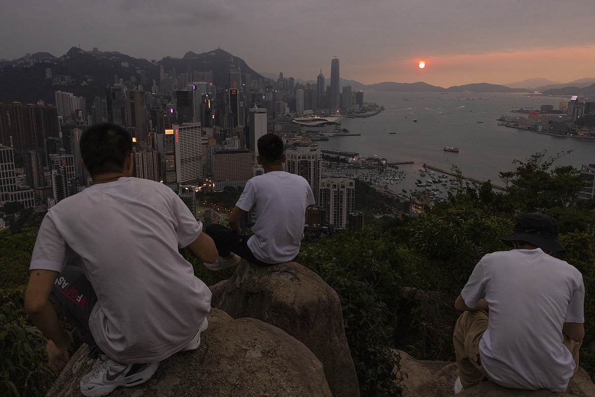 Mainland Chinese tourists look at sunset from a hill in Hong Kong, April 26, 2023. Living in Hong Kong today means juggling contradictory feelings. In 20 interviews, many said that when they focus on business indicators and everyday life, they see a recovery gathering pace after years of travel restrictions. But when it comes to anything political, the openness and freedoms that were once hallmarks of the Chinese-ruled former British colony seem permanently gone. (AP Photo/Louise Delmotte, File)