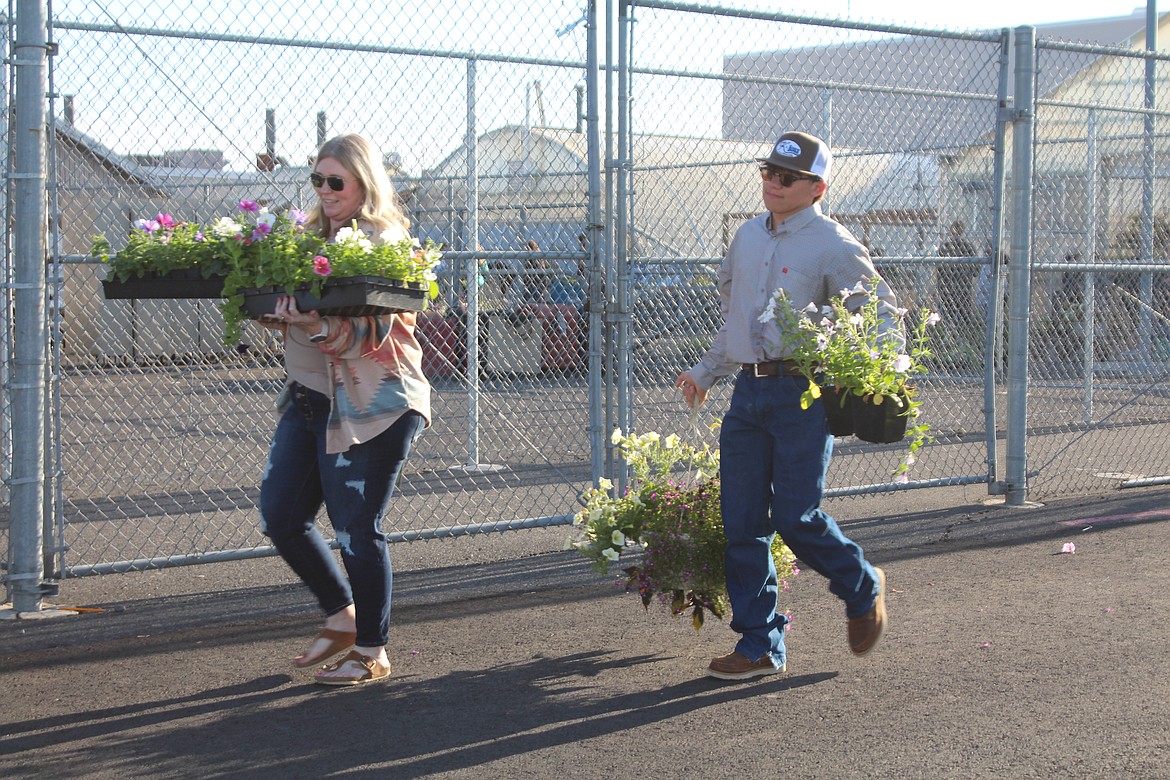 Moses Lake High School FFA member Enrique Orozco, right, helps Kelli Yager, left, load her purchases from the MLHS FFA plant sale Friday morning.