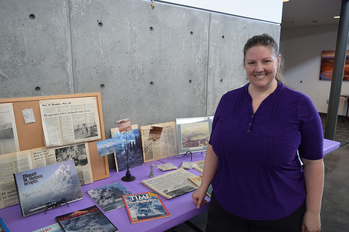 Stephanie Massart, regent of the Karneetsa Chapter of the National Society of the Daughters of the American Revolution, stands in front of a display of books, magazines and newspapers all highlighting how local residents coped with the eruption of Mt. St. Helens on May 18, 1980.