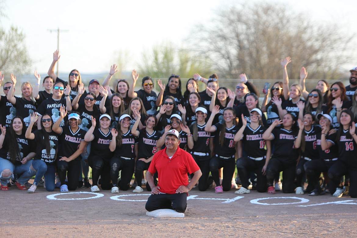 Current and former Othello softball players gather around Head Coach Rudy Ochoa, in red, for a photo during a ceremony honoring the longtime coach’s final regular season home game. Ochoa is retiring at the end of the 2023 season after a 27-year career at Othello.