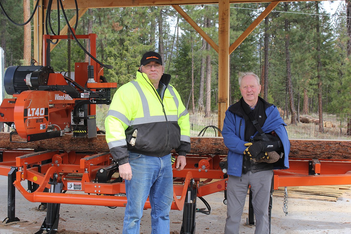 Ron Denn (left) and Don Felstet stand next to the saw that is the heartbeat of Felstet Corporation Bandsaw Sawmill that can handle logs up to 21 feet in length and 36 inches in diameter. This fills a niche for customers to have specialty cuts from their own timber in smaller quantities and faster turnaround time. (Monte Turner/Mineral Independent)