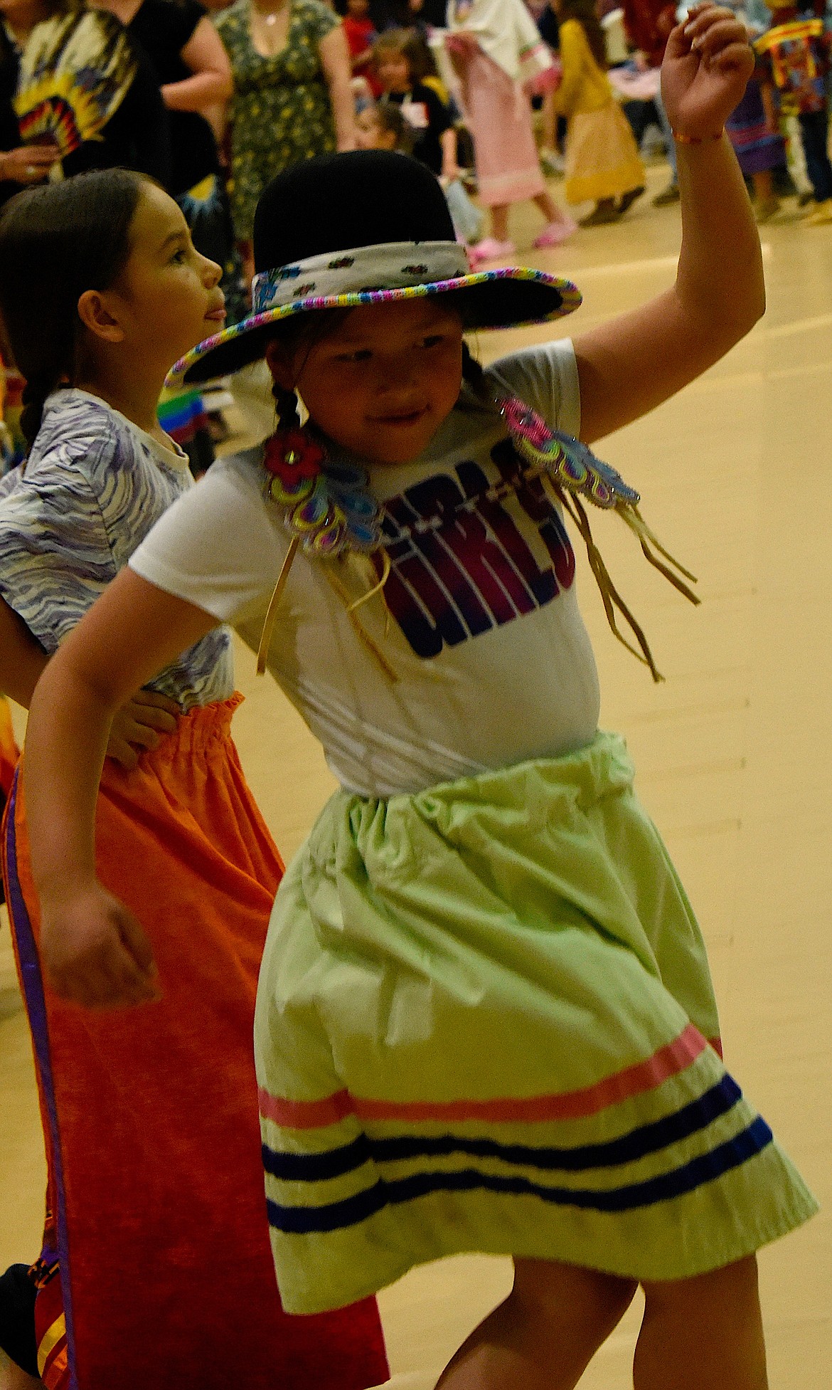 A young dancer with a beaded hat brim enjoys the pow-wow.