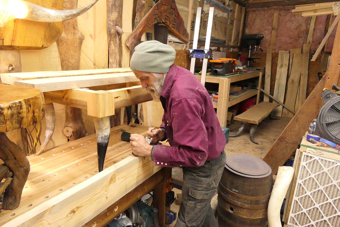 Sanders County artisan Charles Vogliardo hand-plans a piece of wood that will be part of a table with steer horn legs. (Chuck Bandel/VP-MI)