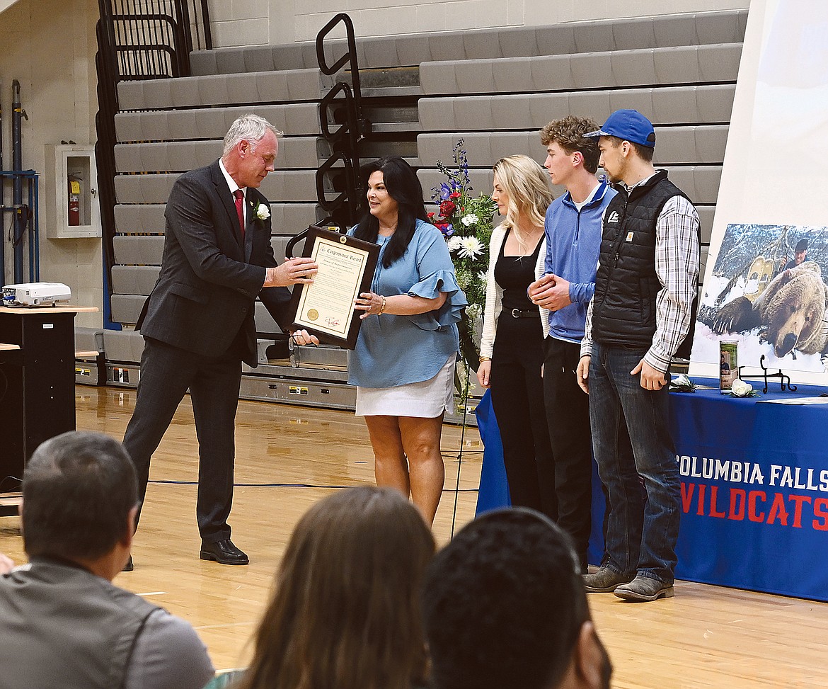 Congressman Ryan Zinke, left, gives Tonia, Hailey, Reggie and Lane Sapa a framed copy of the Congressional Record recognizing Bill Sapa during a celebration of life Saturday at the Columbia Falls High School.