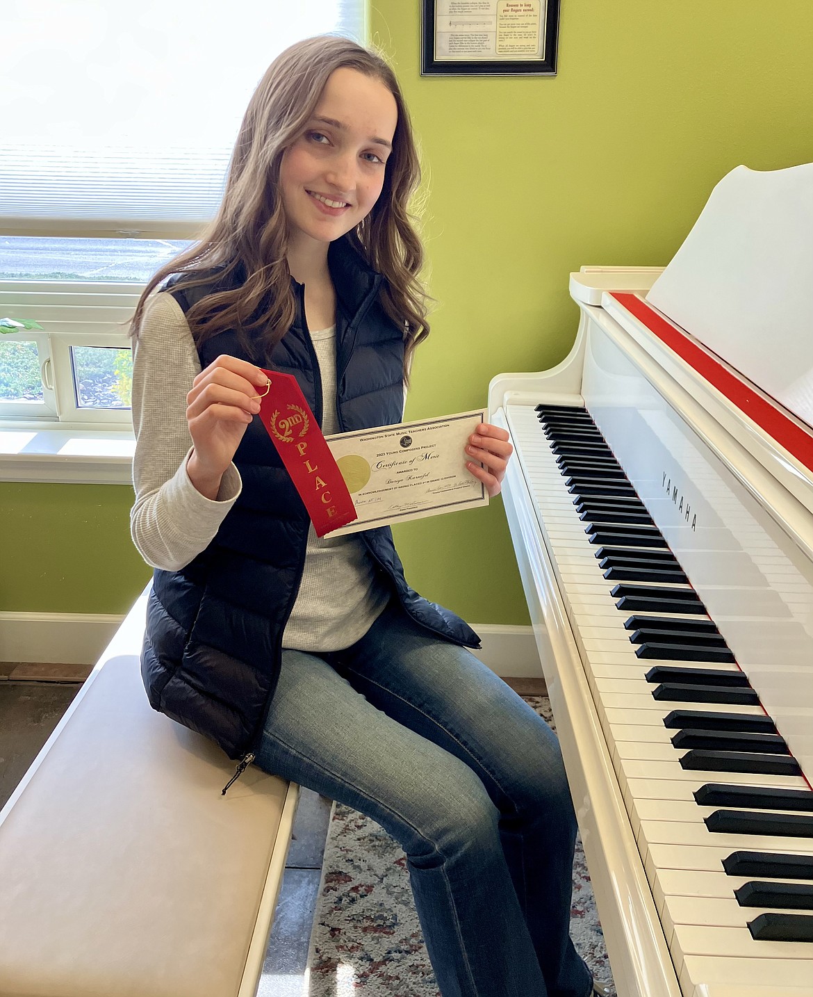 Dariya Karnafel sits at the piano and displays the award she won for her composition, "Sea of Memories." This year was Karnafel's second participating in the Washington State Music Teachers Association's Young Composers Project.