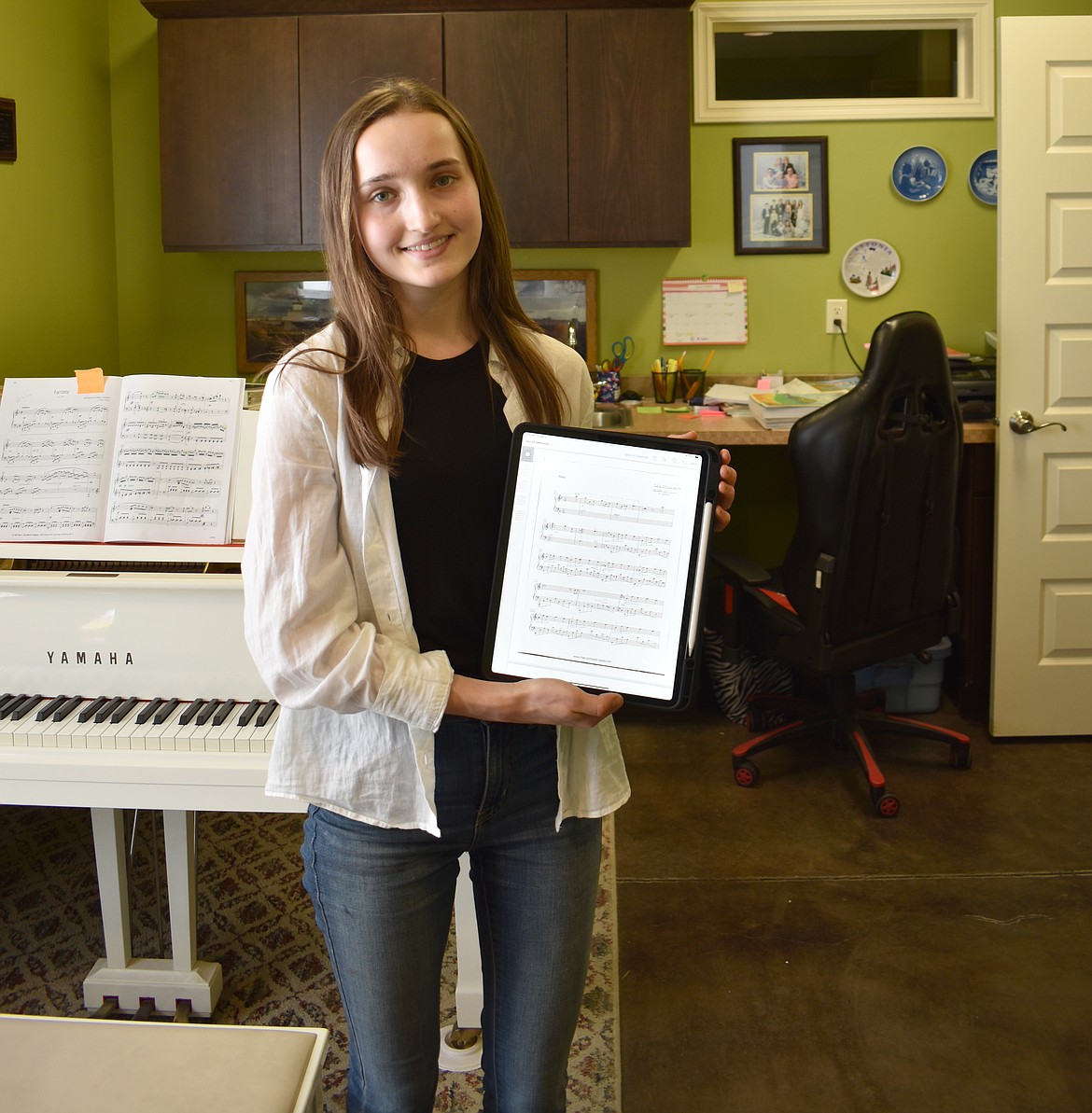 Moses Lake music student Dariya Karnafel holds up an image of the handwritten manuscript for her composition “Sea of Memories,” which recently won second place in the Young Composers Project competition.