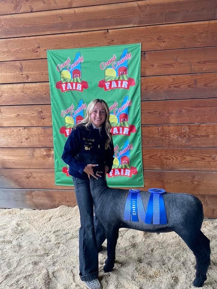 A Moses Lake High School FFA member shows off the results of a summer’s work, her award-winning lamb, at the 2022 Grant County Fair.