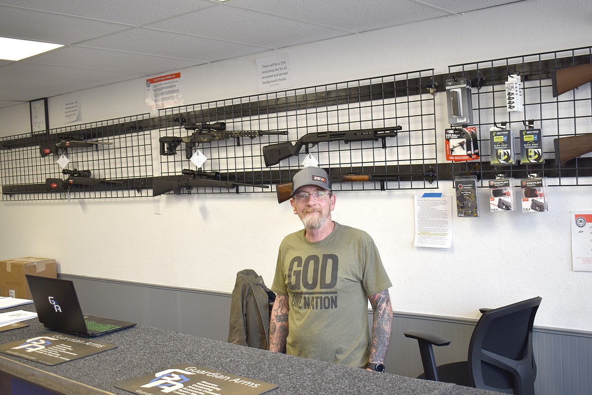 Bruce Davis, owner of Guardian Arms in Moses Lake, stands behind the counter of his shop Thursday. Guardian Arms is one of several entities suing the state over the recently-enacted assault weapons ban.