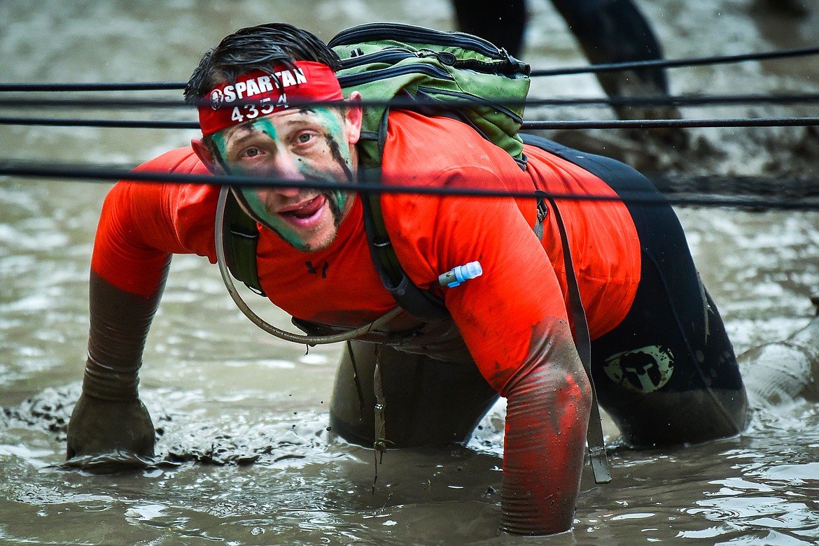 Brian Trubl, of Phoenix, Arizona, crawls through a water obstacle at the Montana Spartan Trifecta in Bigfork on Saturday, May 6. (Casey Kreider/Daily Inter Lake)