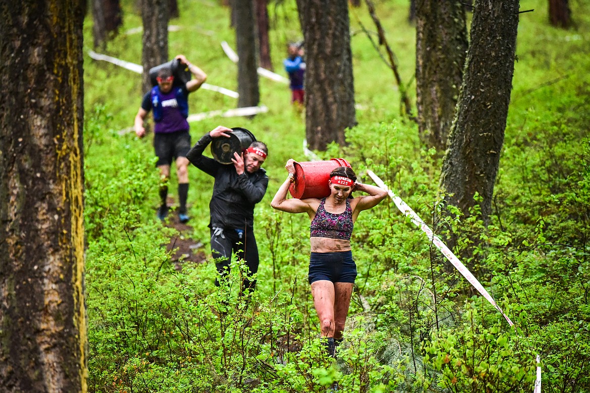 Lacey Bourgois, from Colorado Springs, Colorado, leads competitors down a hill during the bucket carry obstacle at the Montana Spartan Trifecta in Bigfork on Saturday, May 6. (Casey Kreider/Daily Inter Lake)