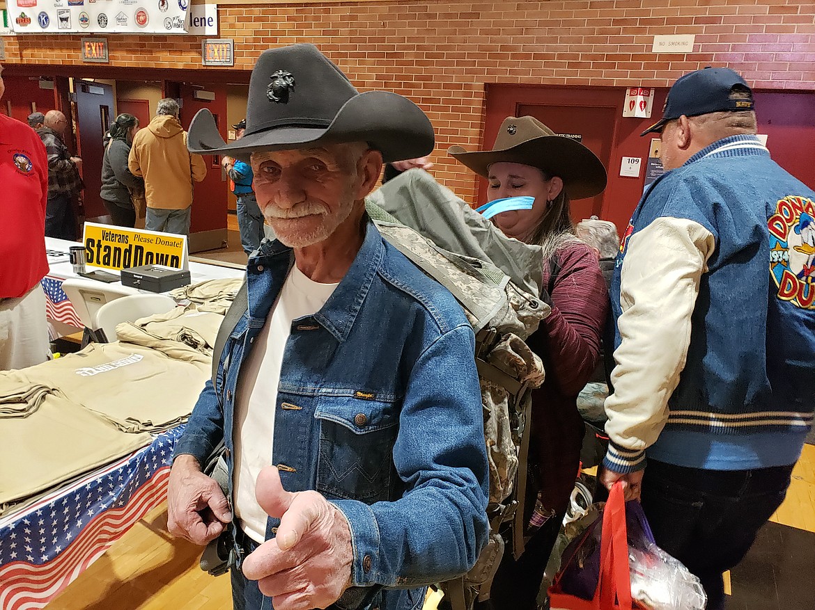 Veteran Dan Cooley waits while his wife, Kimberly, packs his backpack with the brochures, pamphlets and tokens they gathered from the North Idaho Veterans Stand Down on Saturday at North Idaho College. Veteran Bruce Mariani walks around them with his own bags of helpful information and his new tomato plant.