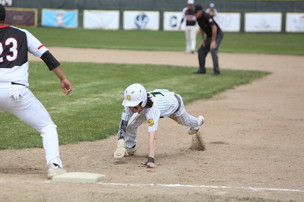 Quincy sophomore Caleb Coduti dives back to first base to survive a pick-off attempt.