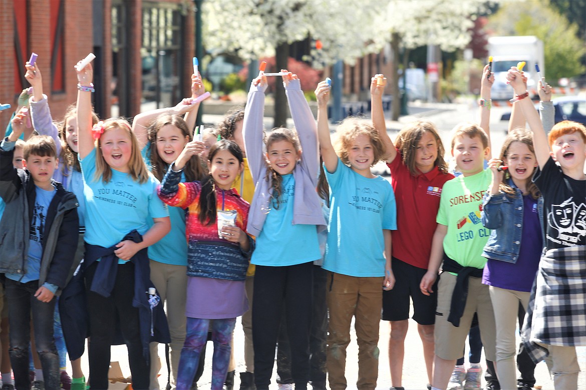 Sorensen Magnet School of the Arts and Humanities third graders hold up chalk after drawing fruits and vegetables for the 5th Street Farmers Market on Tuesday in downtown Coeur d'Alene.