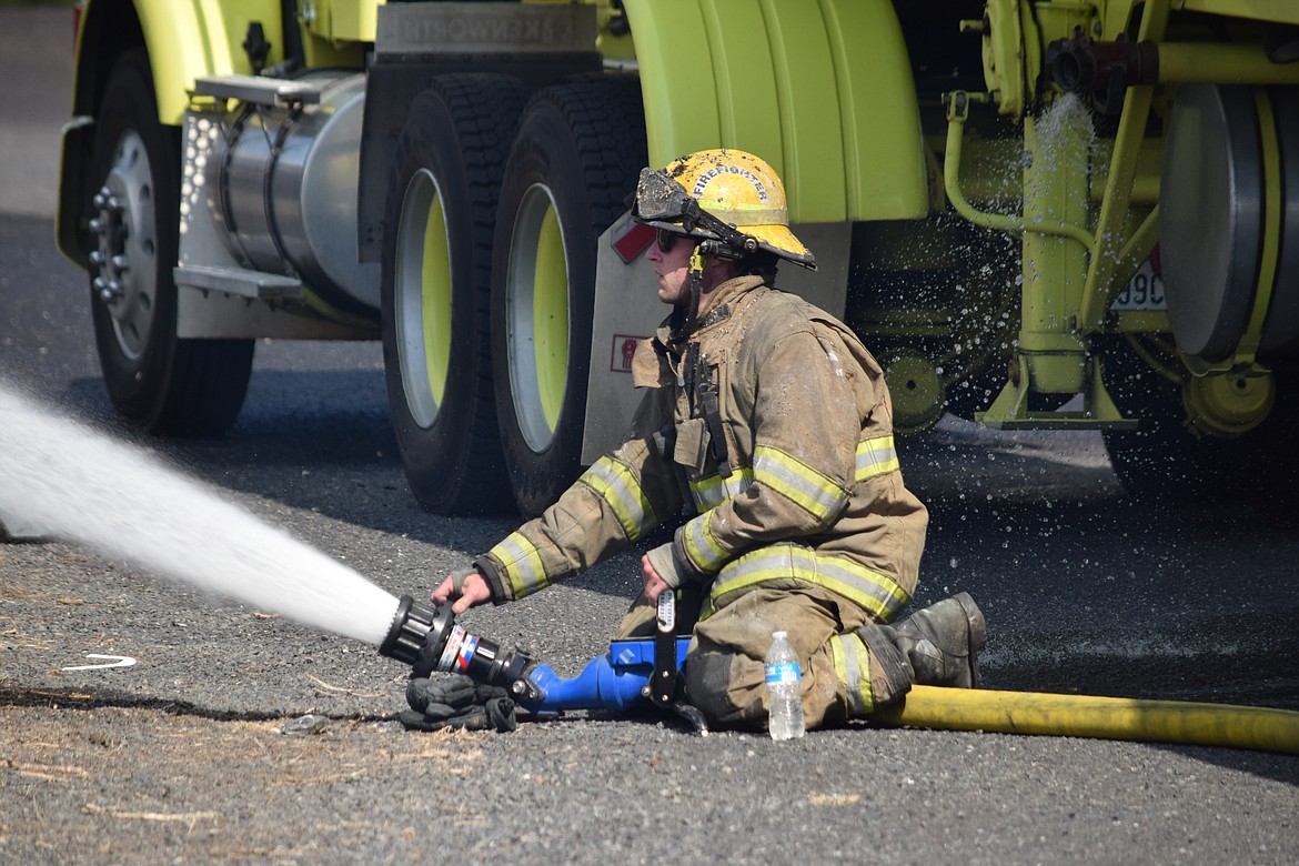A Grant County Fire District 5 firefighter aims a high-pressure hose at a house fire outside Moses Lake on Tuesday.