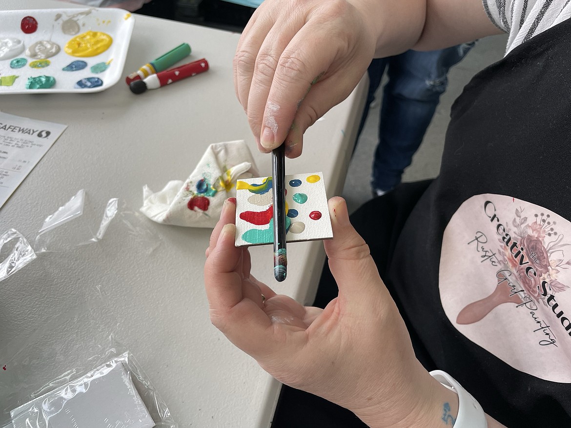 Tessa Johnstone smears dabs of paint on a tiny canvas as part of a dollhouse decorating project.