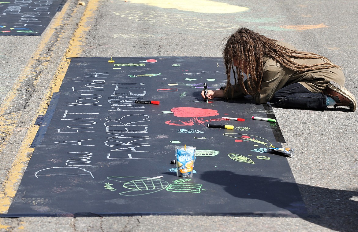 Couredge Solmonson, Sorensen Magnet School of the Arts and Humanities third grader, works on a poster for the 5th Street Farmers Market on Tuesday in downtown Coeur d'Alene.