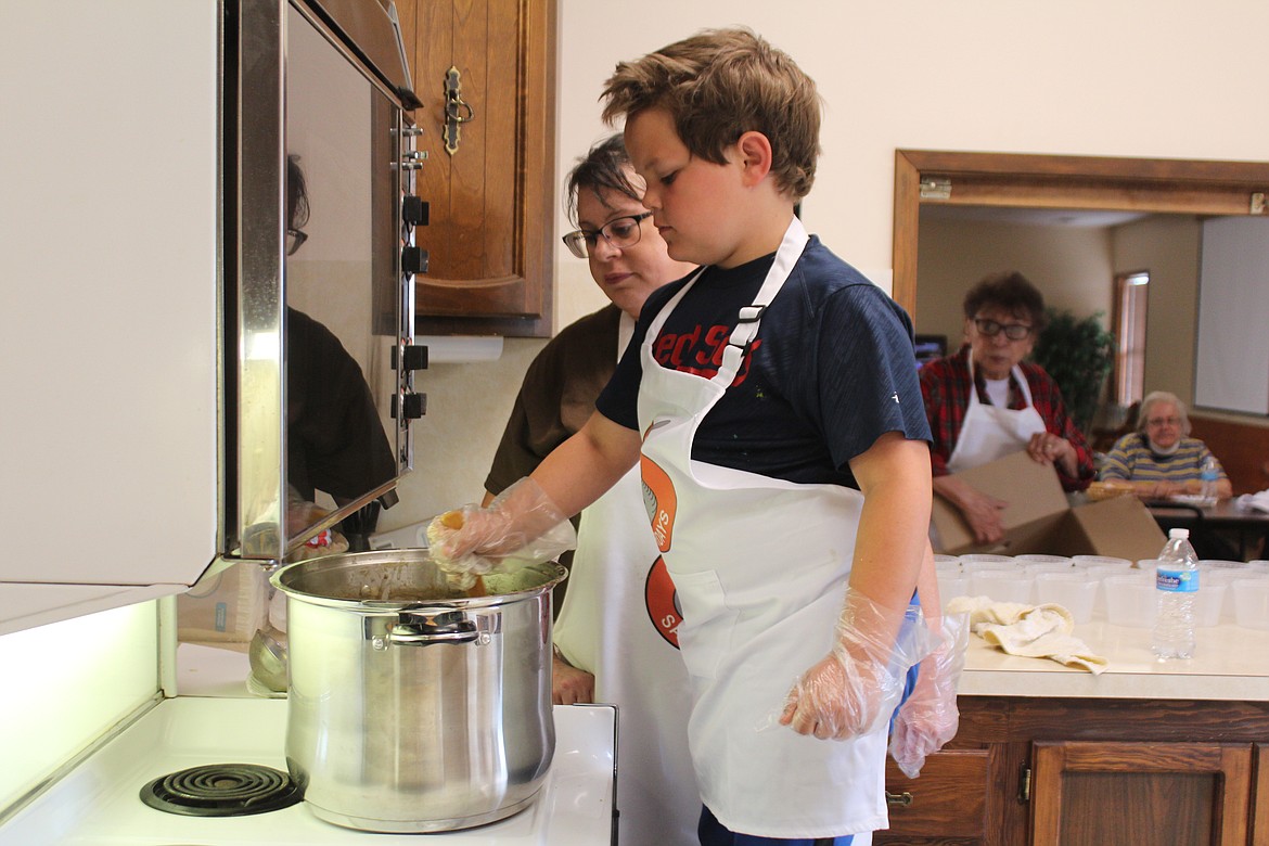 Eight-year-old Asher Schober, front, helps his friend Trinette Mullineaux, back, prepare soup for the Soup on Saturdays project.