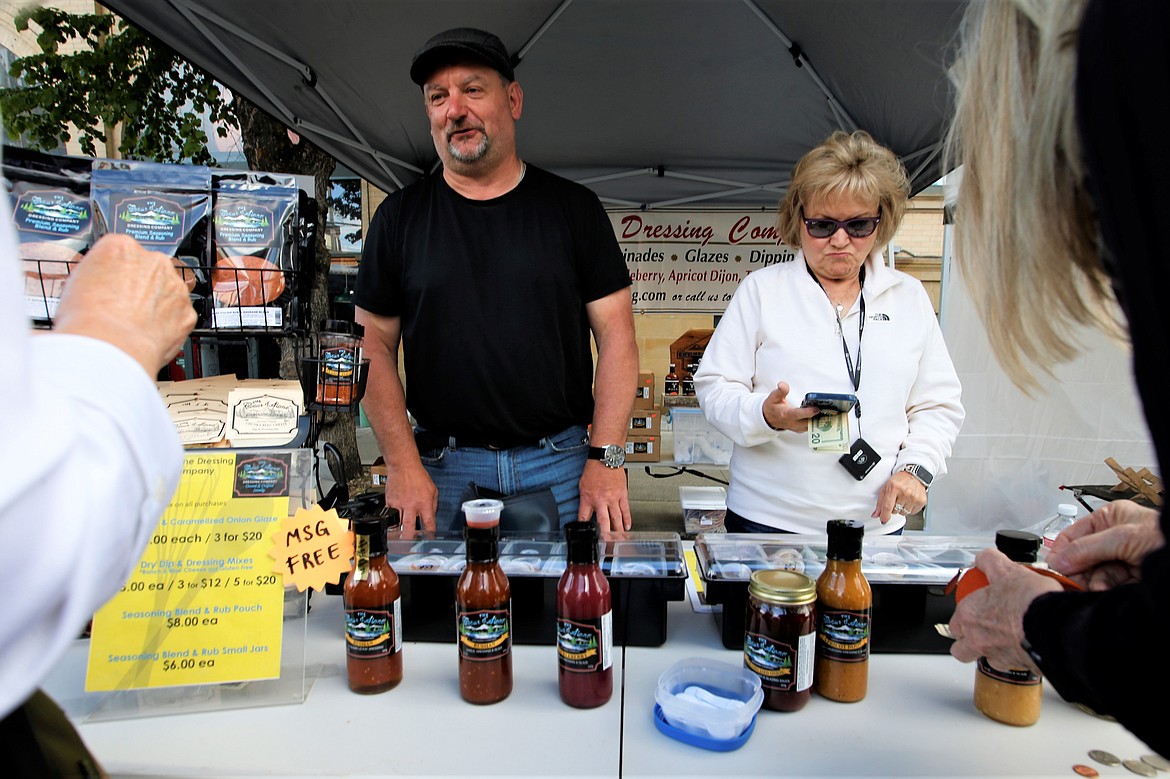 Perry Martin, owner of The Coeur d'Alene Dressing Company, and Nicky Hastings chat with customers at the 5th Street Farmers Market on Wednesday.