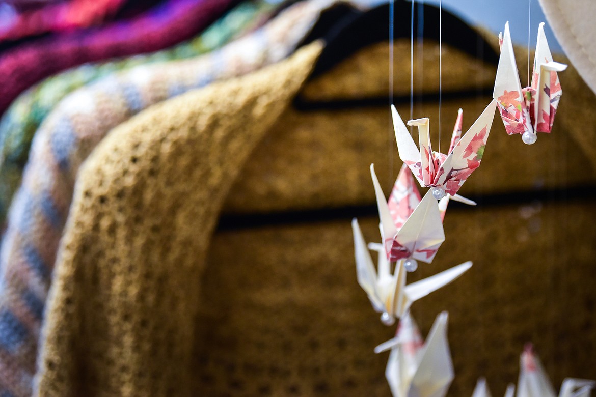 A Washi Origami Crane Mobile hangs in front of shawls made from hand-spun and hand-dyed yarn by Joni Walker of Tomorrow's Heirlooms at Bluebird & Honeybee Mercantile in Bigfork on Wednesday, May 10. (Casey Kreider/Daily Inter Lake)