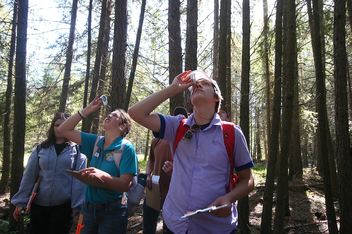Lake Pend Oreille Alternative High School junior Kaiden Harper, center, and Orofino High School junior Shaylee Taylor peer through clinometers as they measure tree height Thursday morning during the Idaho State Forestry Competition at Farragut State Park. More than 300 students from across the state participated.