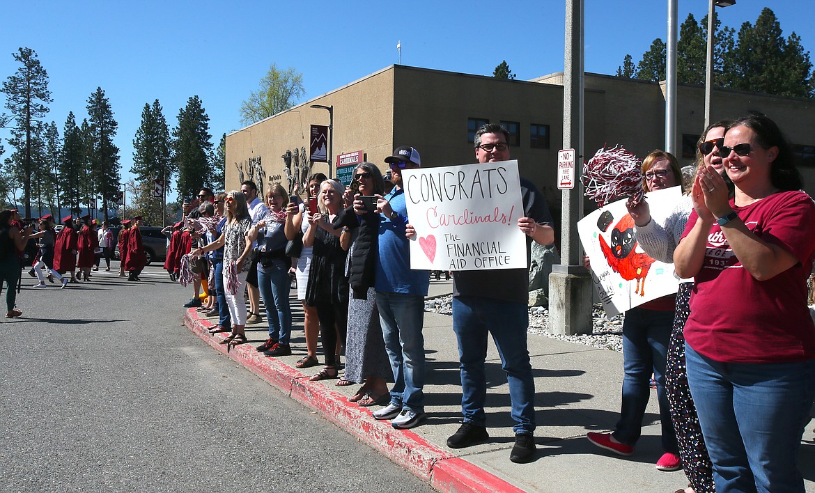 People cheer for North Idaho College graduates Friday morning as they march from Boswell Hall to the gym for their commencement ceremony.