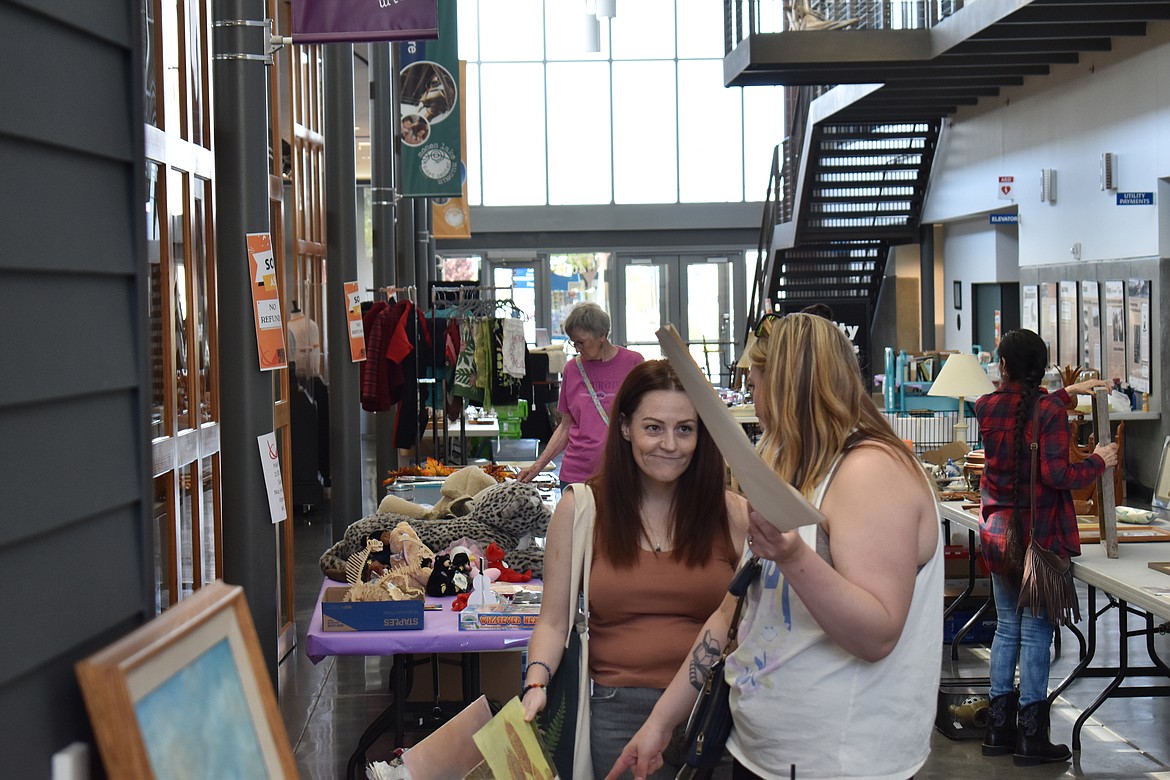 Selena Holland, left, and Cait Withers, both of Moses Lake, check out the artwork for sale at the Moses Lake Museum & Art Center’s Rusty Mammoth Sale Saturday.