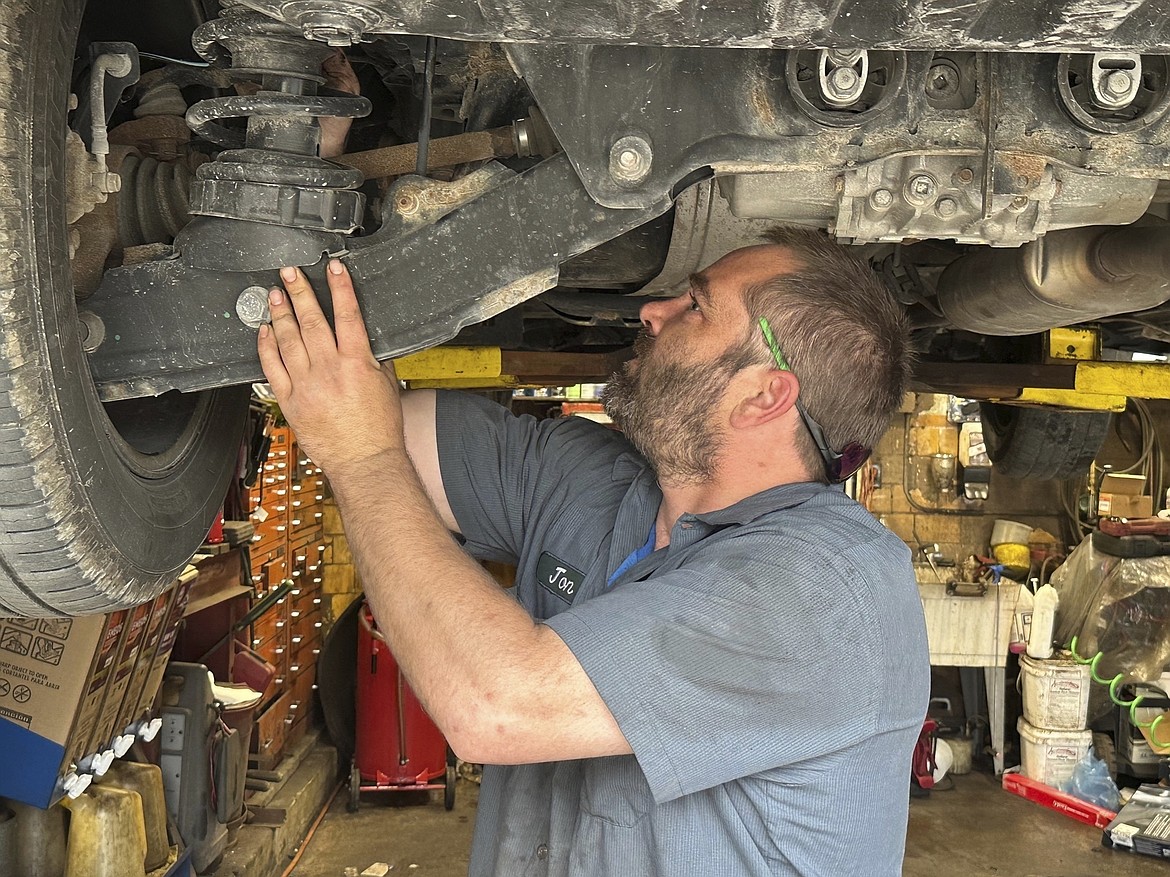 Mechanic Jon Guthrie inspects the underside of a 2014 Honda Ridgeline pickup truck at Japanese Auto Professional Service in Ann Arbor, Michigan. People are keeping their vehicles longer due to shortages of new ones and high prices. That drove the average U.S. vehicle age up to a record 12.5 years in 2023, according to S&P Global Mobility. (AP Photo/Tom Krisher)