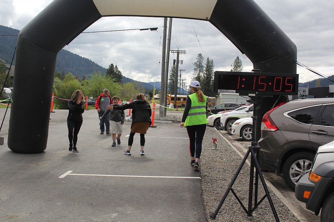 Danial Crider follows his son, Korbin who is in 3rd grade at Alberton as he is congratulated at the Fun Run Finish Line. The Cider Guys enjoyed themselves last Wednesday and for Korbin, the best part was being able to see the river during the event. (Monte Turner/Mineral Independent)