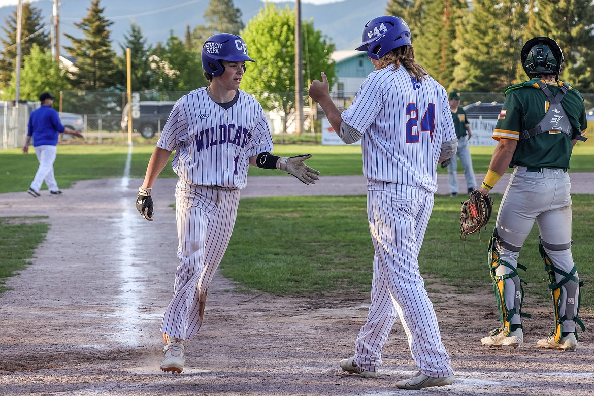 Cody Schweikert congratulates Dawson Juntunen on a run at home last week against Whitefish. (JP Edge photo)