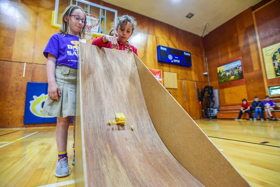 St. Matthew's School third-graders Louise Francischetti and Madison Strause release their pasta mobile, a vehicle constructed entirely of pasta and glue, down a ramp in hopes that it will stay intact as part of teacher Susie Rainwater's K-5 science class on Wednesday, May 17. (Casey Kreider/Daily Inter Lake)