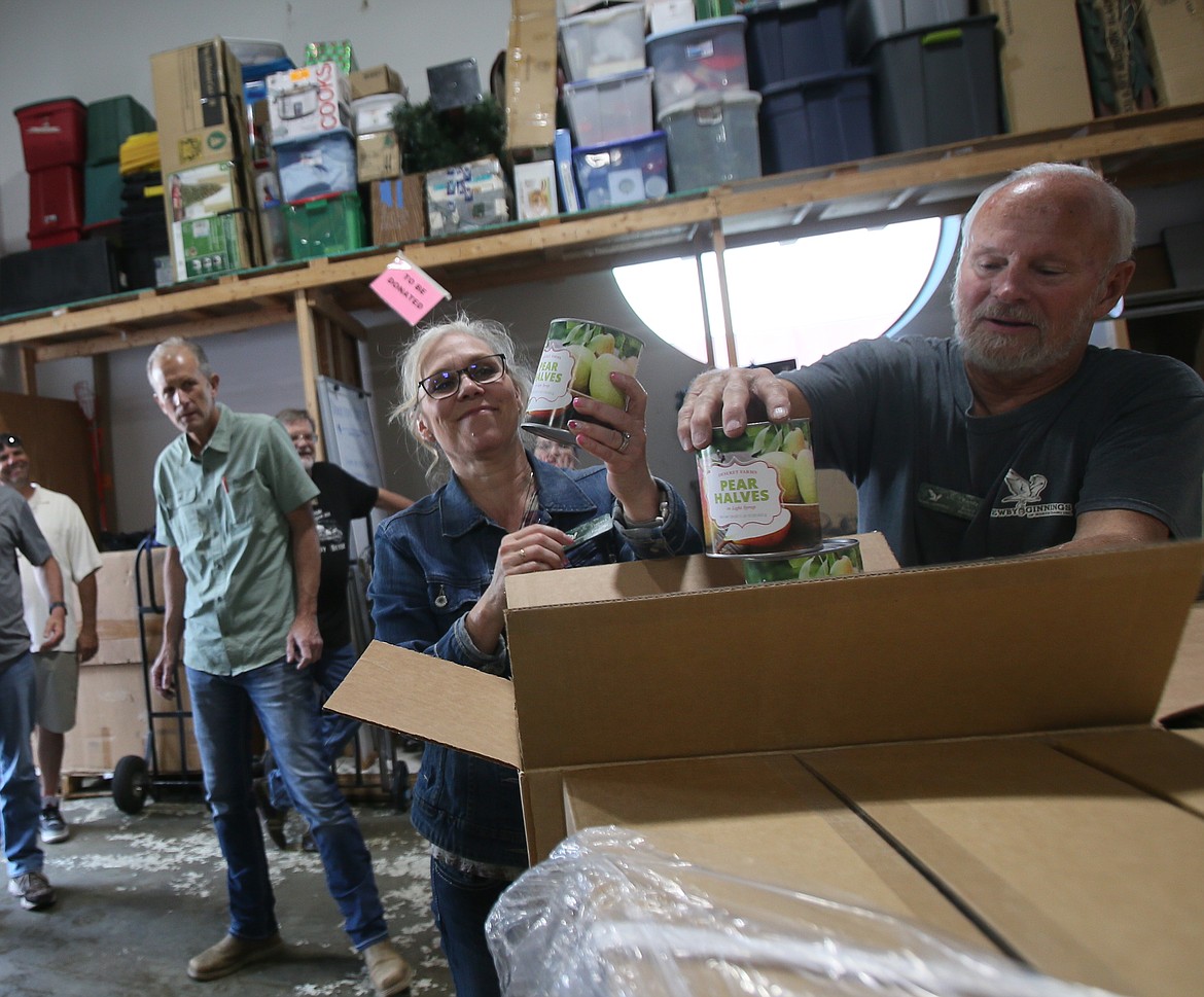 Theresa Hart and Randy Whittenburg of Newby-ginnings of North Idaho begin unpacking cans of pears May 17 after receiving 24,000 pounds of food donations from members of the Church of Latter-day Saints.